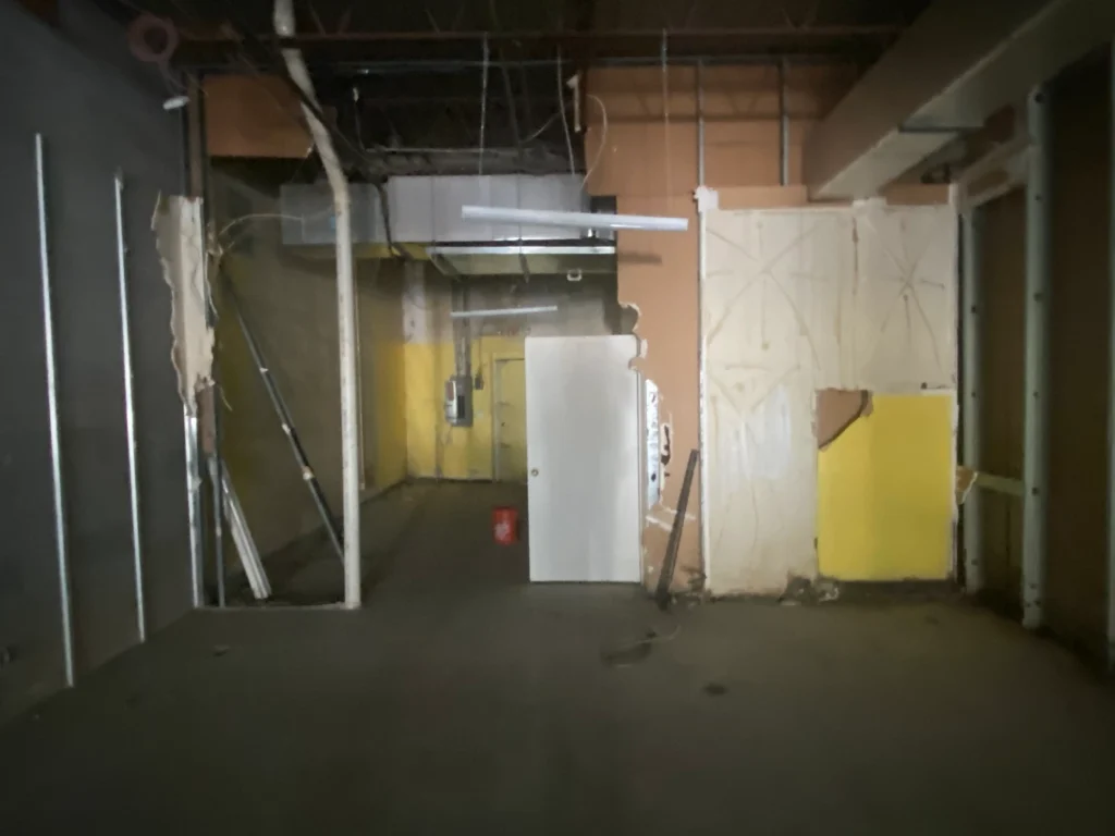 A hallway featuring bright yellow walls and a closed door at the end,