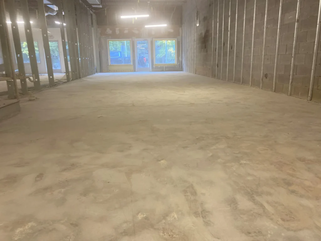 A spacious room featuring bare concrete floors and walls