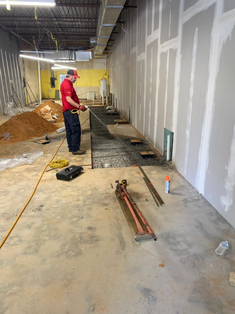 A man is working on a concrete floor inside a building
