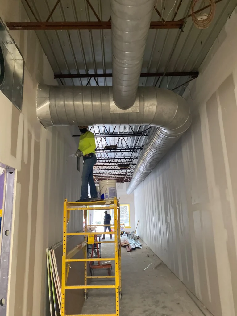 A large pipe in a room alongside a ladder