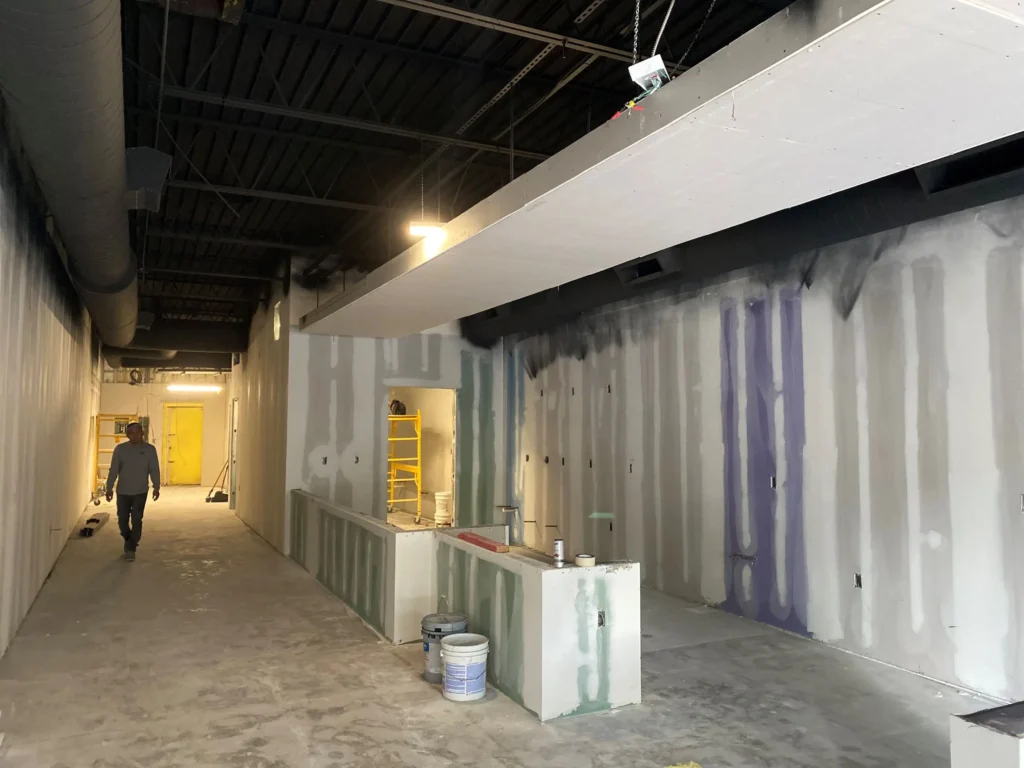 A man walks through a hallway surrounded by construction equipment