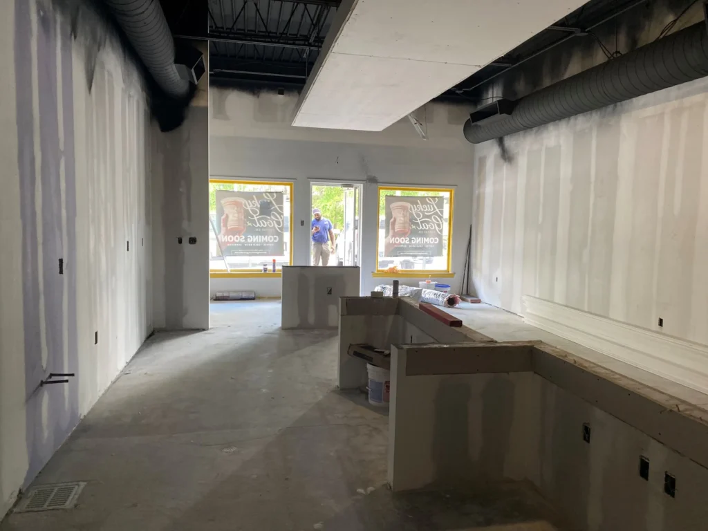 A room featuring a large window and a wall fully covered in drywall,