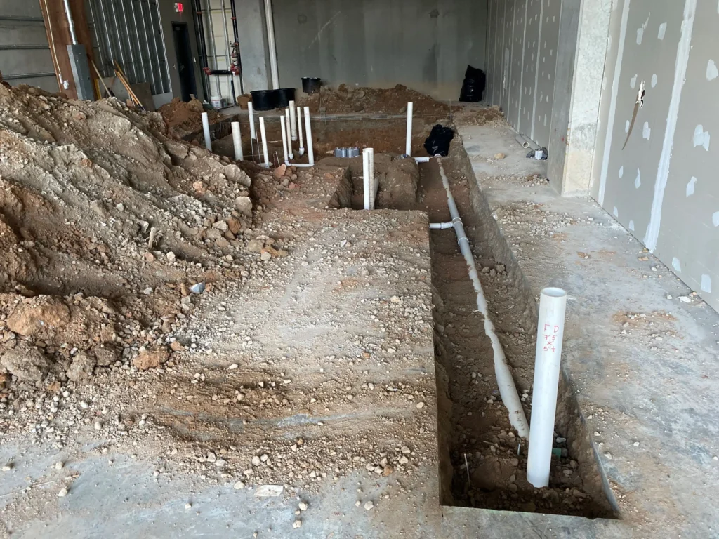 An interior space with a dirt floor and visible pipes