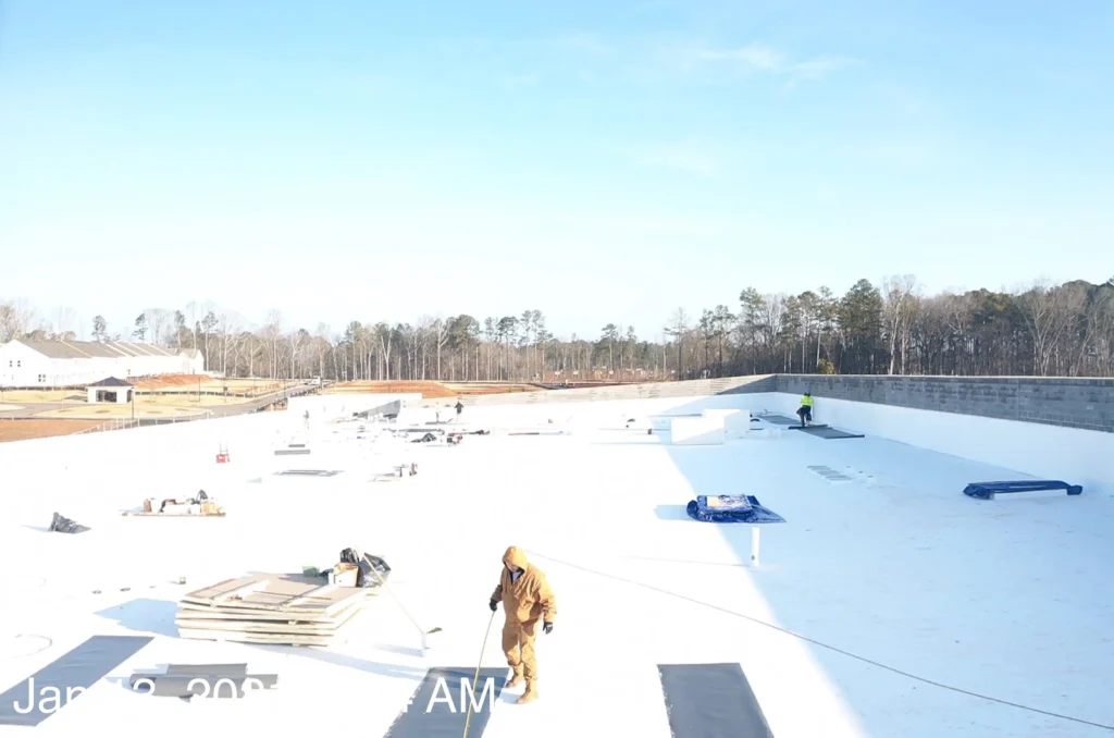 Construction workers on a large white roof