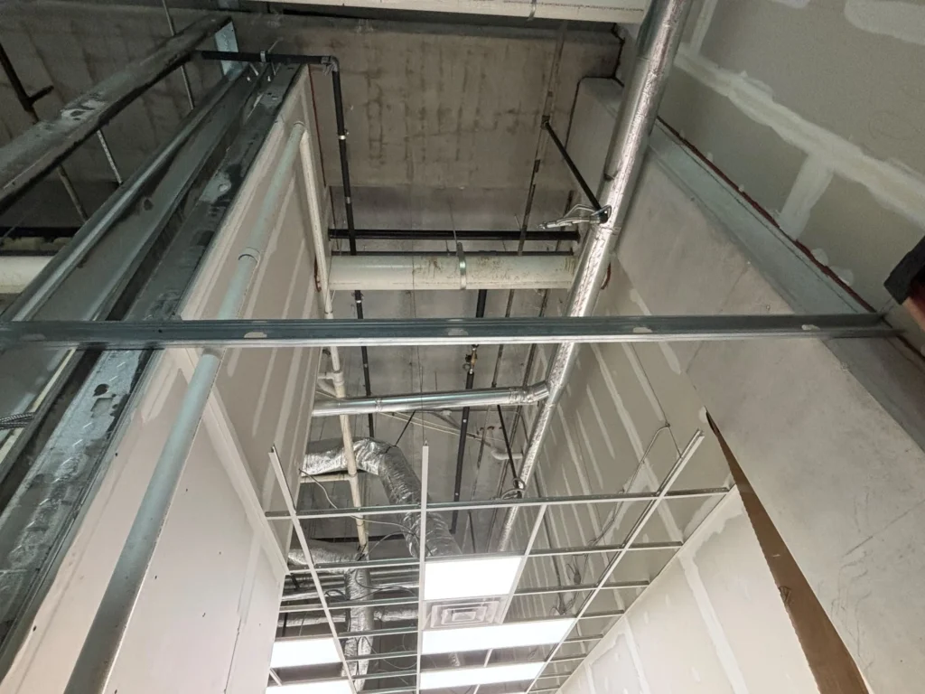 In a cluttered room with visible pipes and wires