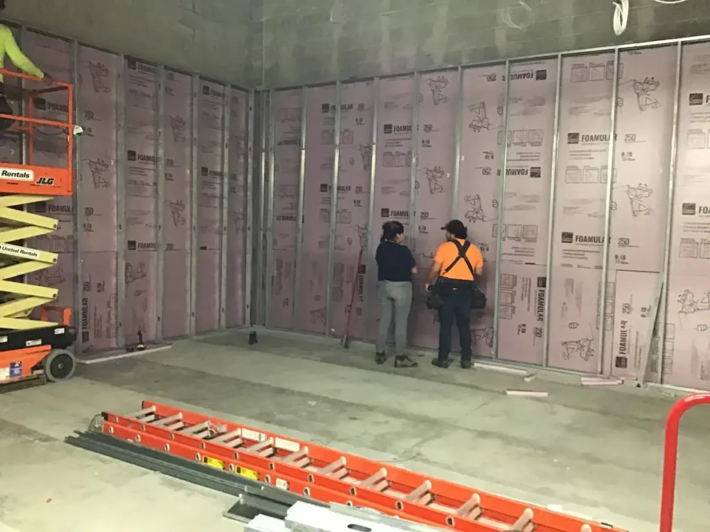 Two men are engaged in wall construction within a building