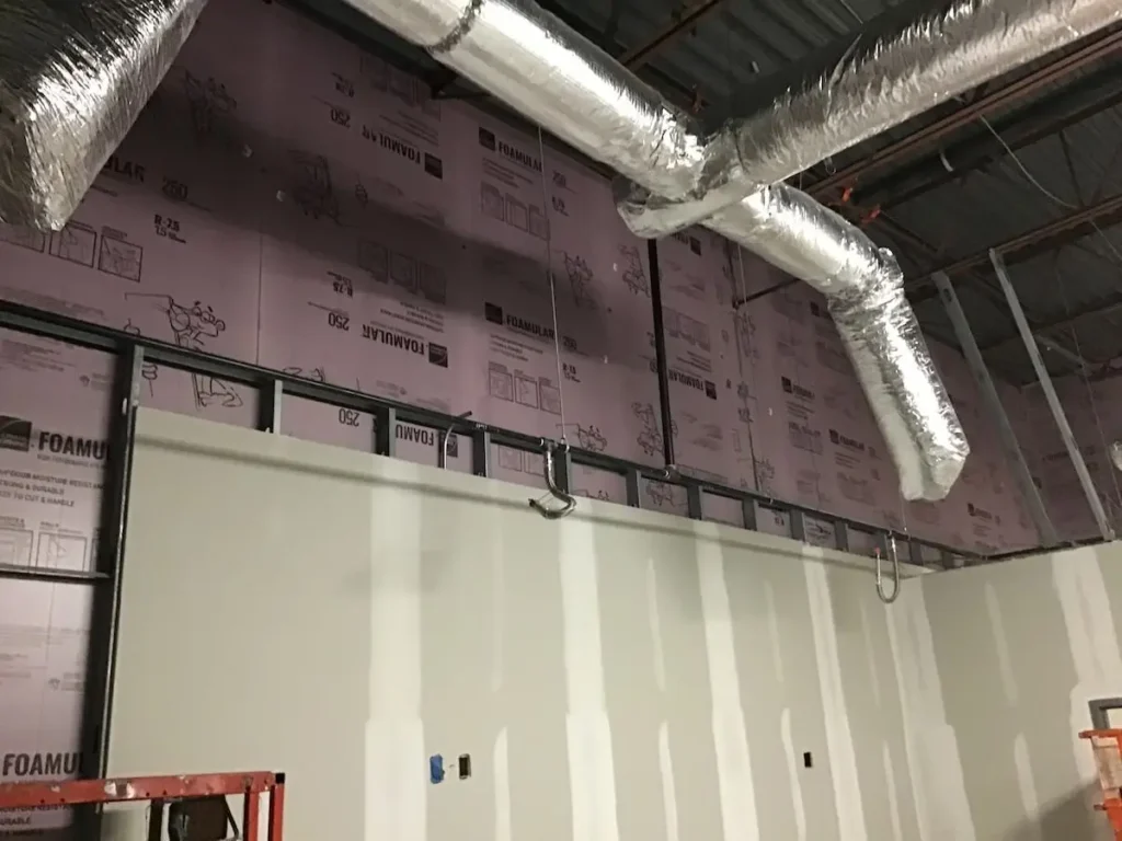 A spacious room with a significant wall lined with insulation