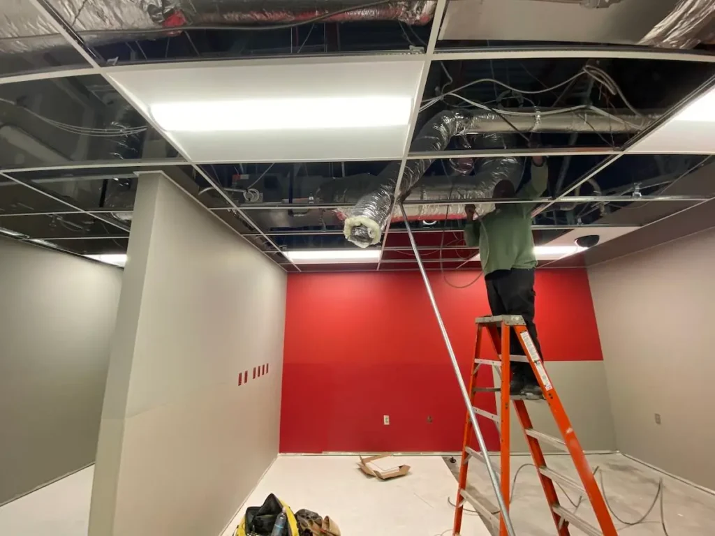 A man is repairing the ceiling in an office