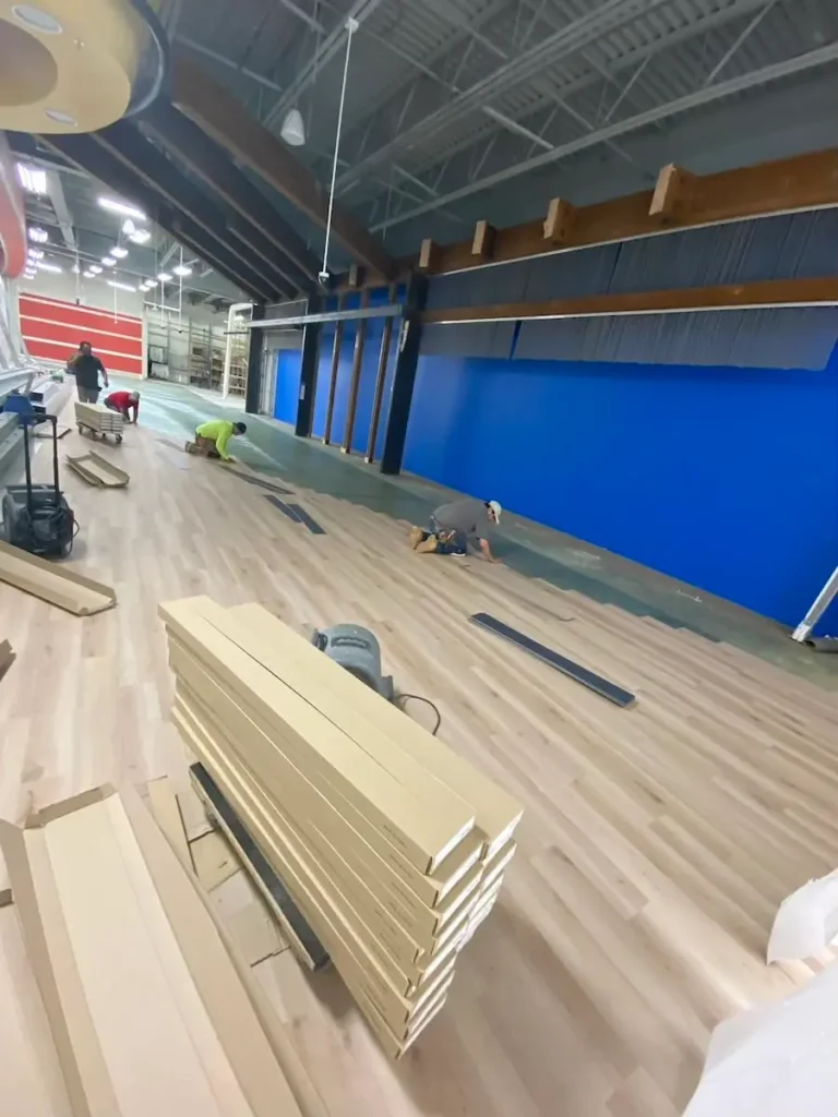 A spacious room featuring wooden floors and a blue wall