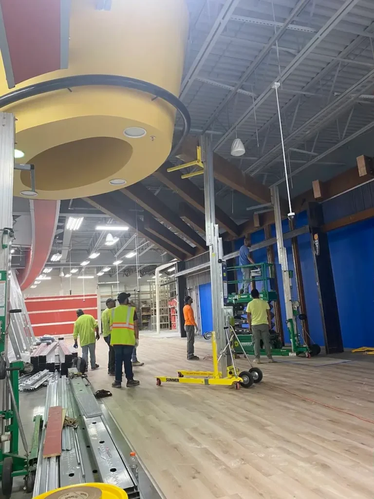 Workers are collaborating on a large yellow object inside a building