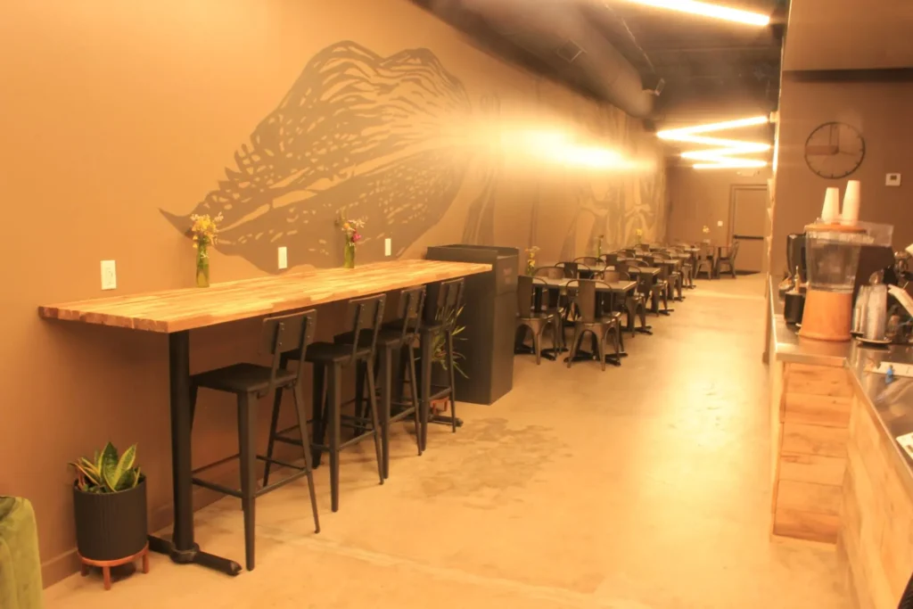 A long bar with stools and tables set up in a restaurant