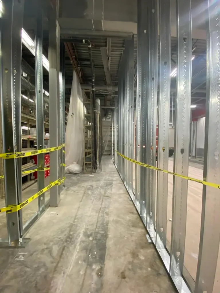 A narrow hallway featuring metal walls and bright yellow caution tape along the floor