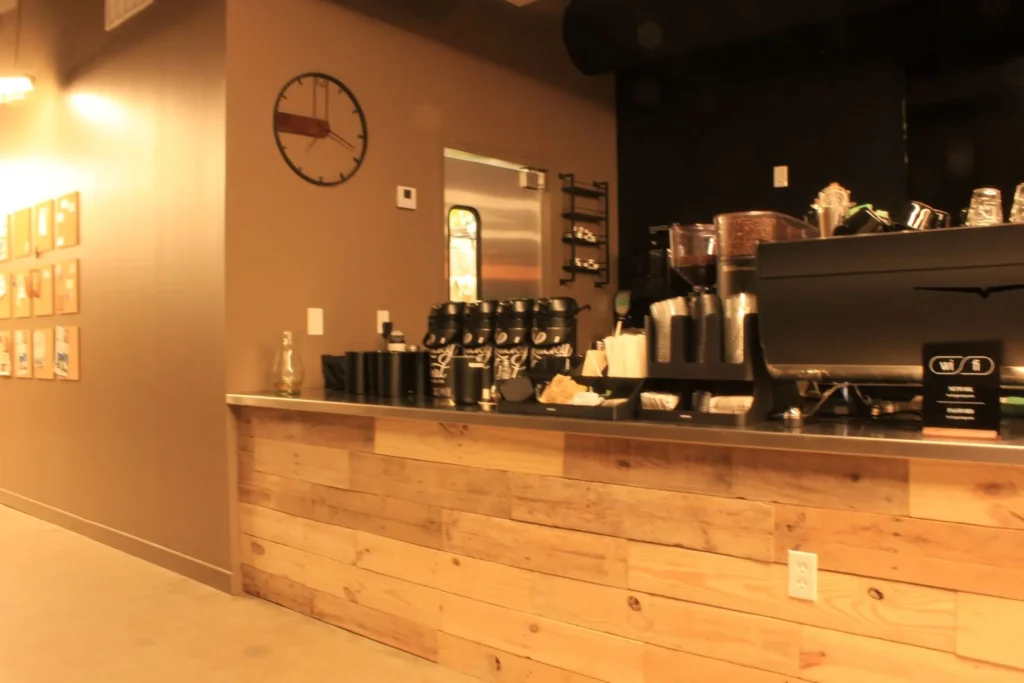 A wooden bar counter with a clock mounted on the wall in a cozy setting