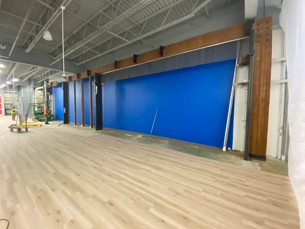 A spacious room featuring blue walls and polished wooden floors
