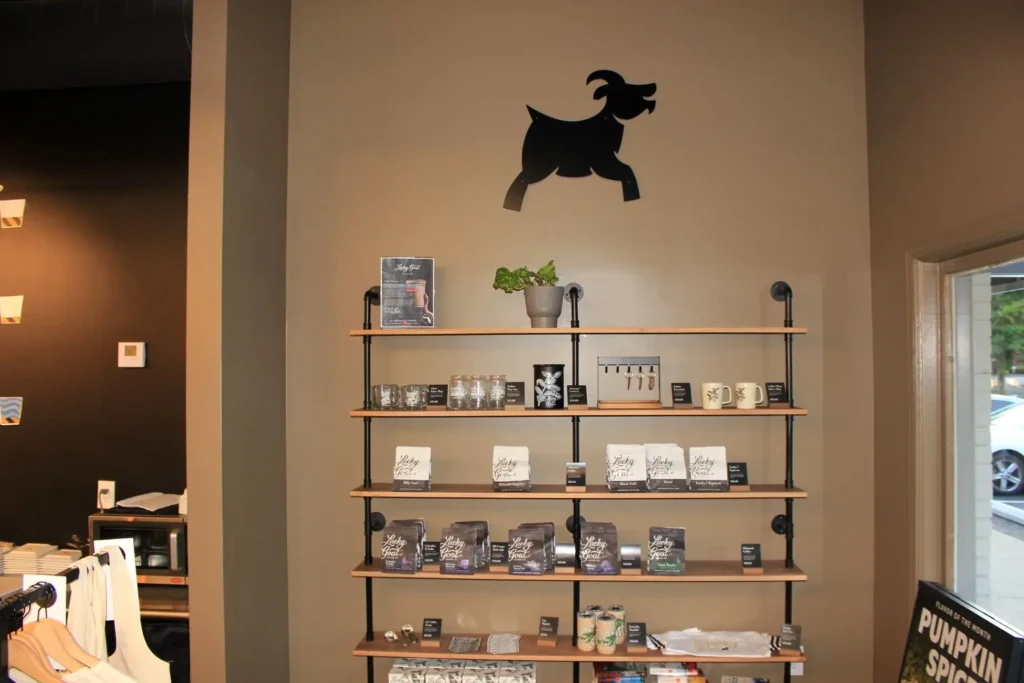 A black goat standing on a wooden shelf