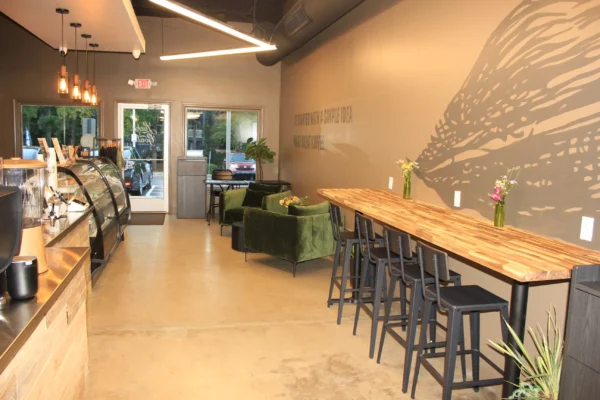 Completed coffee shop interior in Dunwoody GA with high top seating, lounge chairs, and mural wall near the entrance
