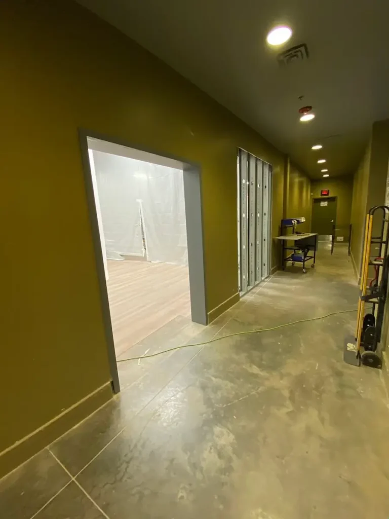 A hallway featuring a door and a wall covered in plastic sheeting