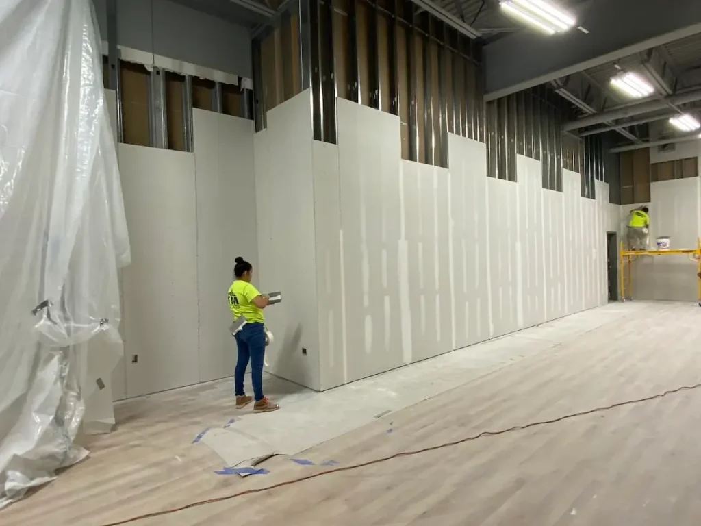A worker is painting the walls of a room with a roller