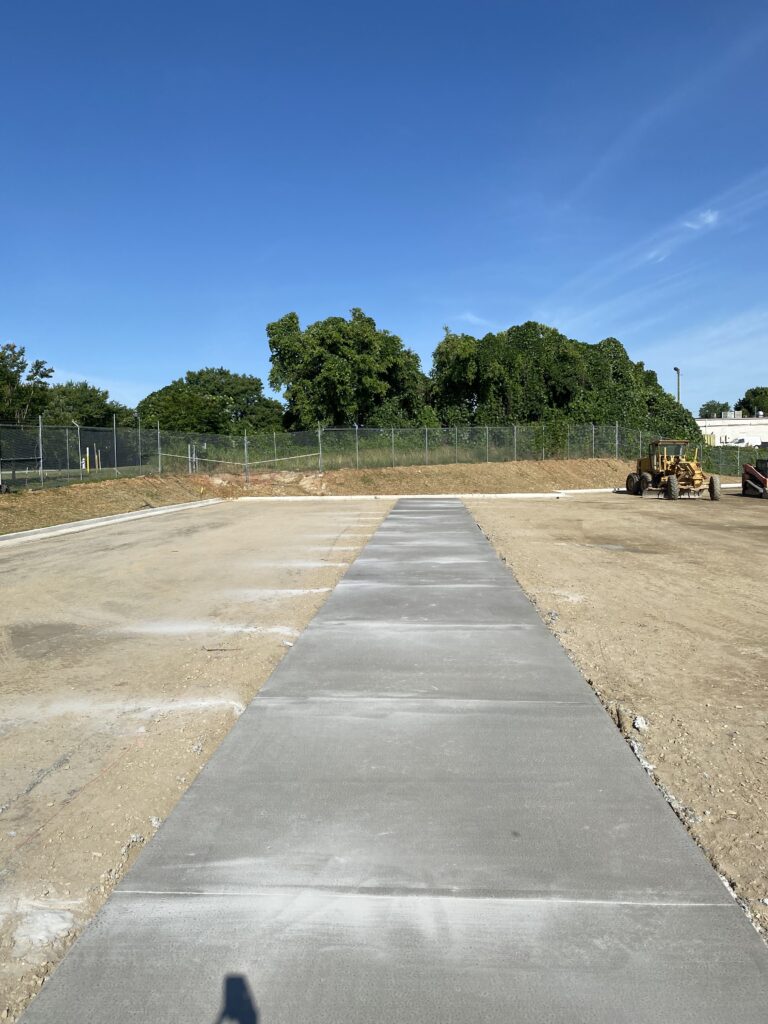 Completed concrete loading apron with parking lot subgrade prepared for asphalt paving