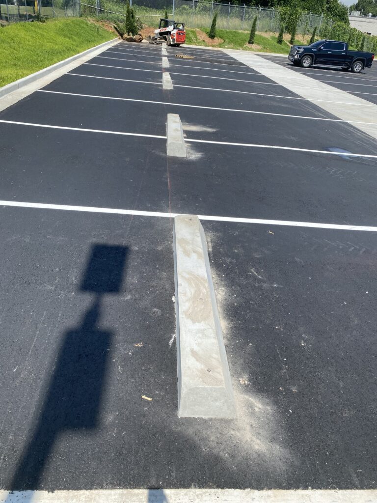Completed commercial parking lot with asphalt paving, pavement striping, concrete curb and gutter, wheel stops, and site improvements