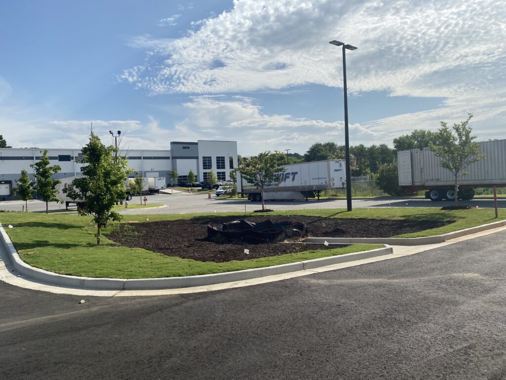 Completed commercial parking lot in Decatur GA with asphalt paving site lighting and landscaped retention pond at front of site