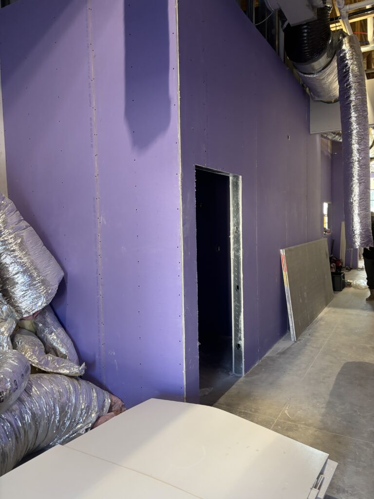 Purple board drywall installed on interior walls and corridors during restaurant construction