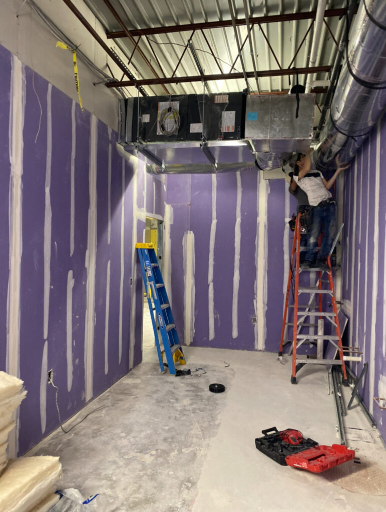 Back-of-house area with moisture-resistant drywall installation and HVAC system rough-in nearing completion