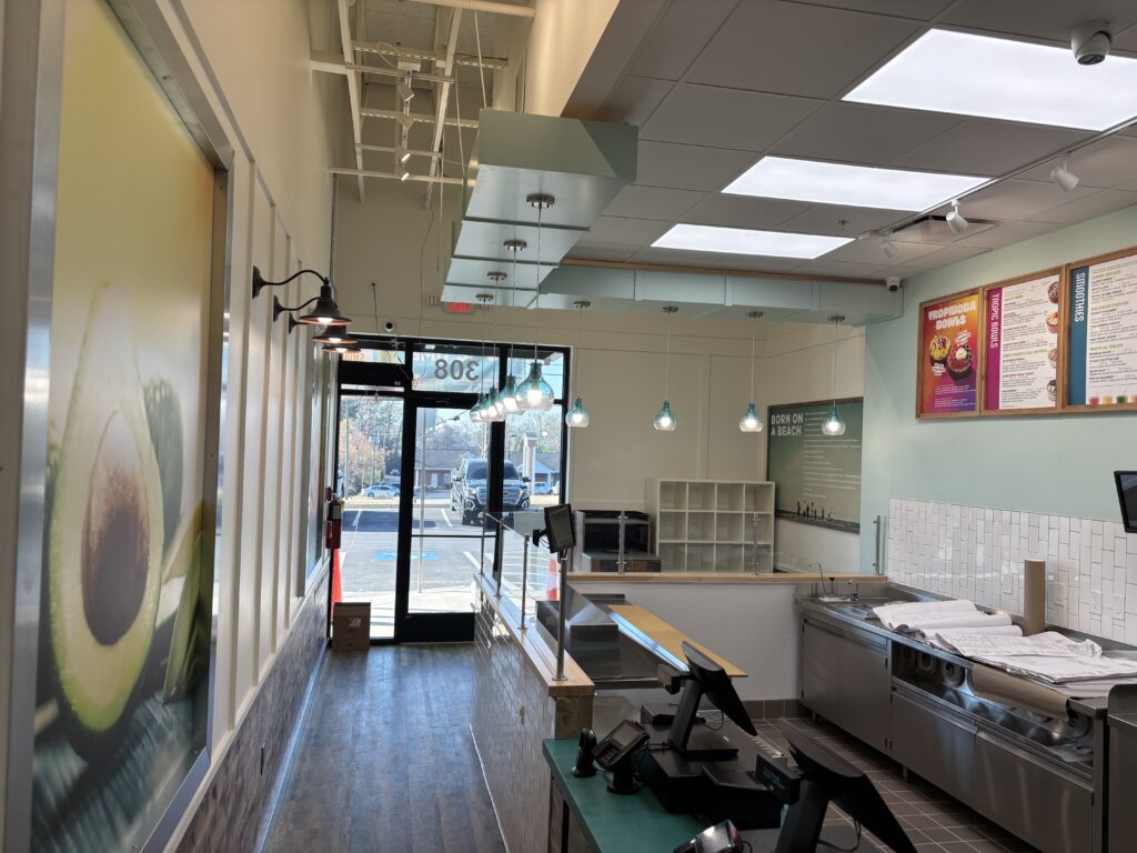 Completed food preparation area featuring quarry tile flooring, stainless steel equipment, tile wall finishes, ceiling grid installation, and service counter construction