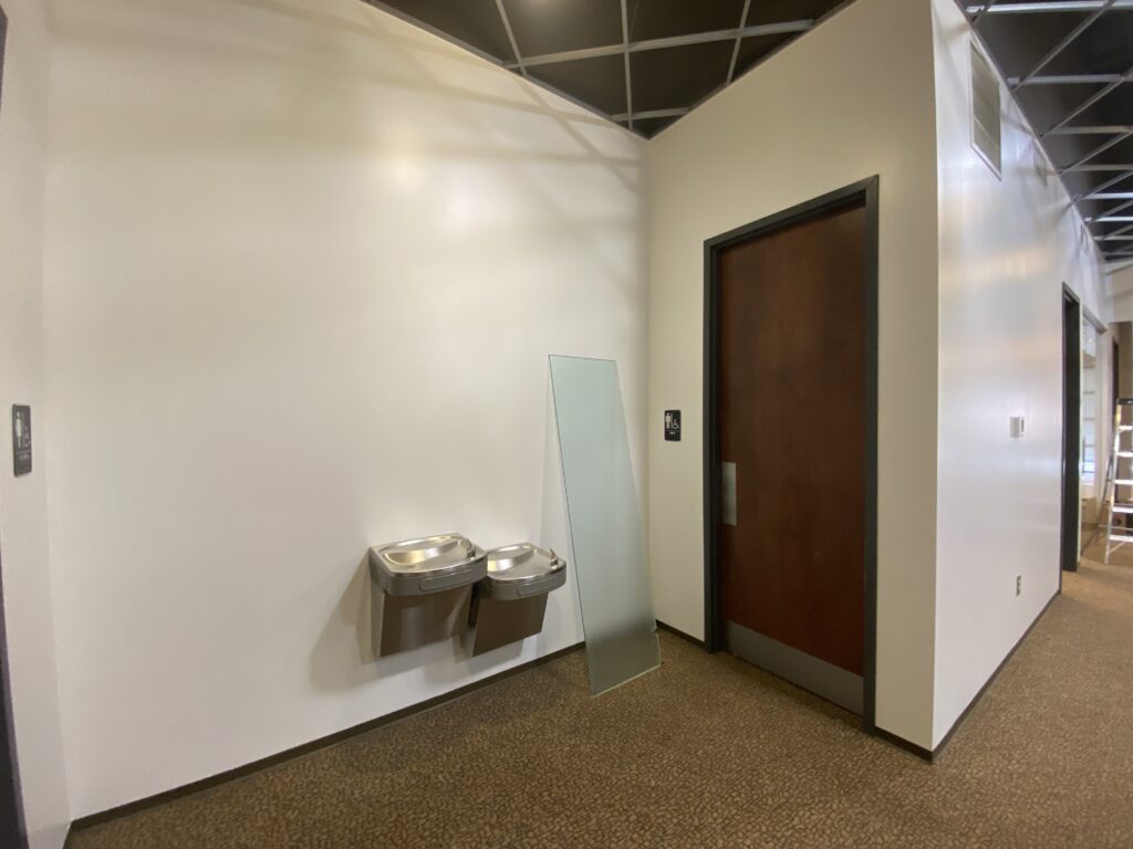 Decatur GA office build out corridor with wall-mounted drinking fountain and solid-core door