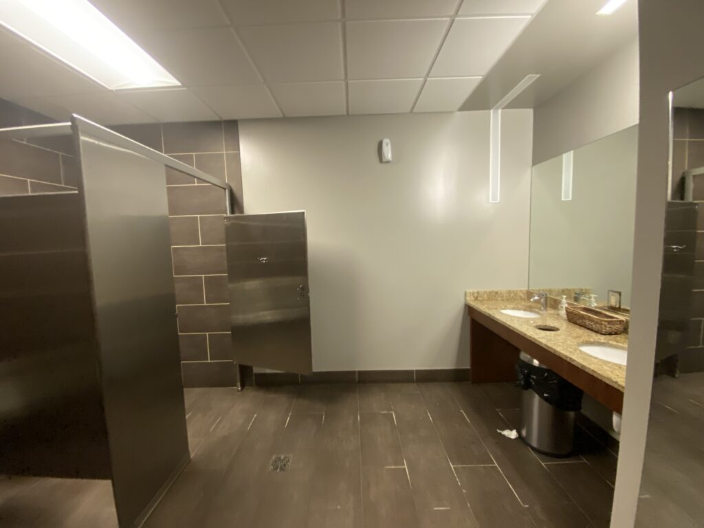 Office restroom in Decatur GA with toilet partitions, solid surface vanity, and tile flooring