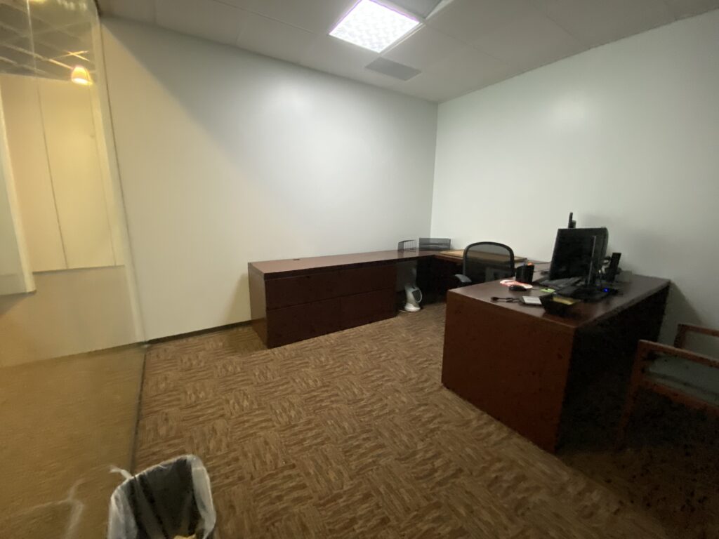 Finished private office in Decatur GA with neutral walls, carpet, and simple desk and storage layout