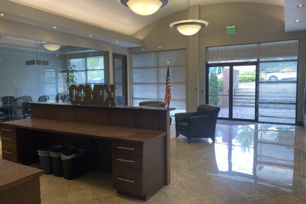 Completed Kemco office build-out reception area featuring custom millwork, polished tile flooring, glass conference room walls, storefront entry doors, and commercial office finishes.